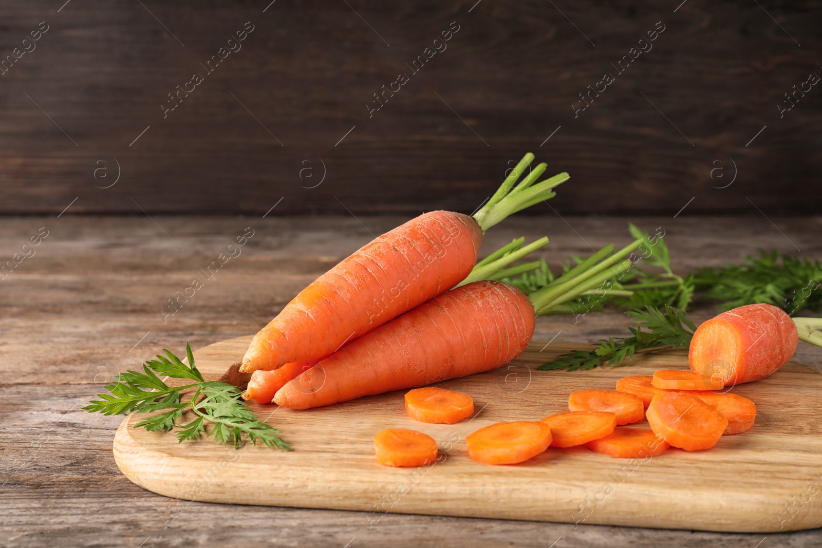 Photo of Board with cut carrot on wooden background