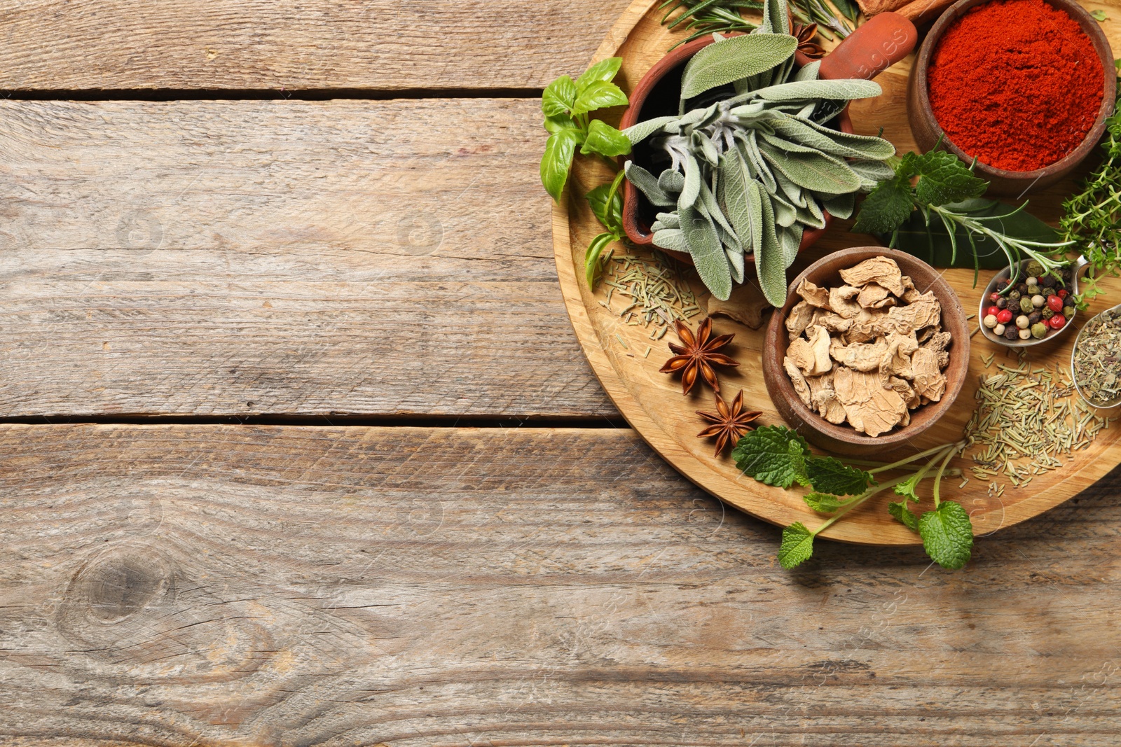 Photo of Different herbs and spices on wooden table, top view. Space for text