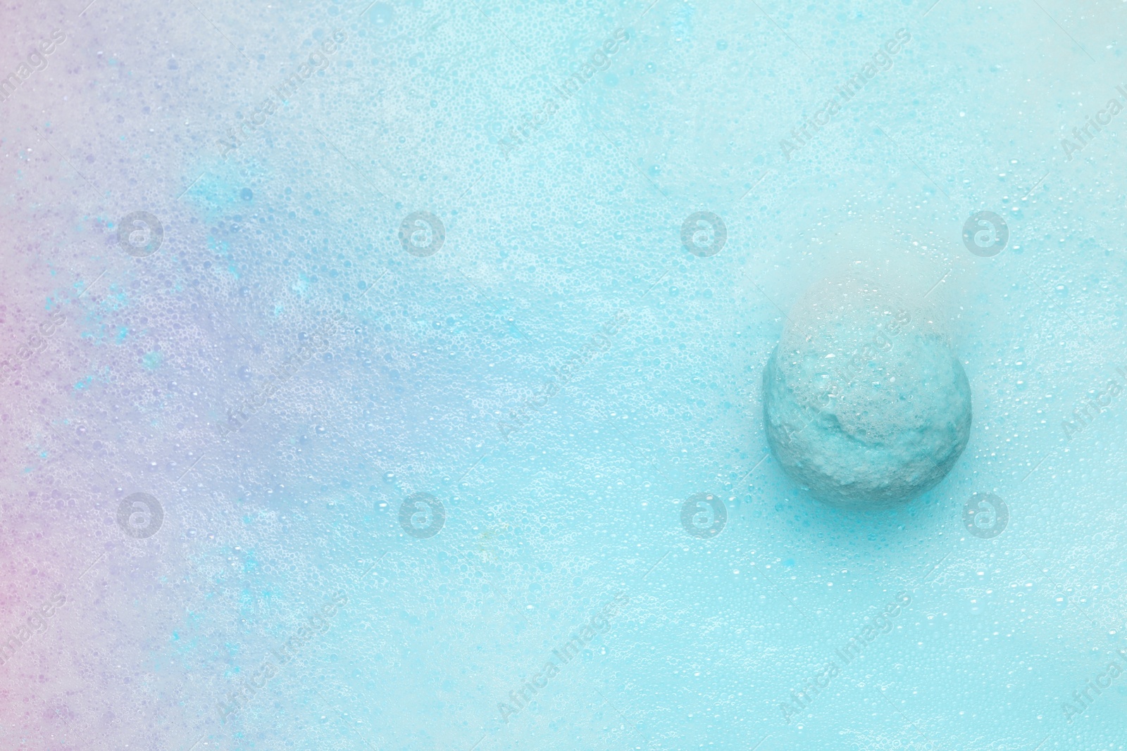 Photo of Light blue bath bomb dissolving in water. Space for text