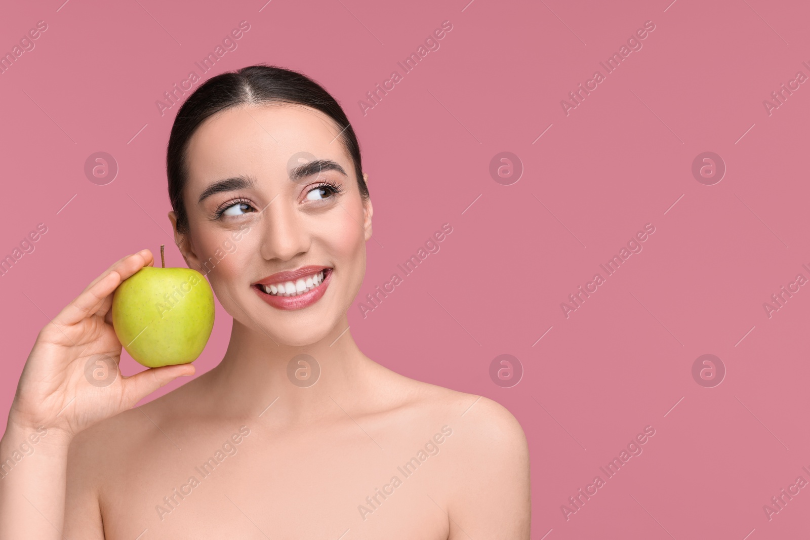 Photo of Beautiful young woman with apple on pink background. Space for text