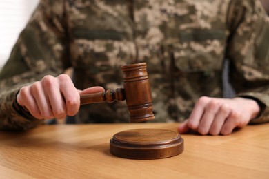 Law concept. Man in military uniform with gavel at wooden table, closeup