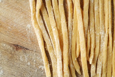 Raw homemade pasta and flour on wooden table, closeup. Space for text