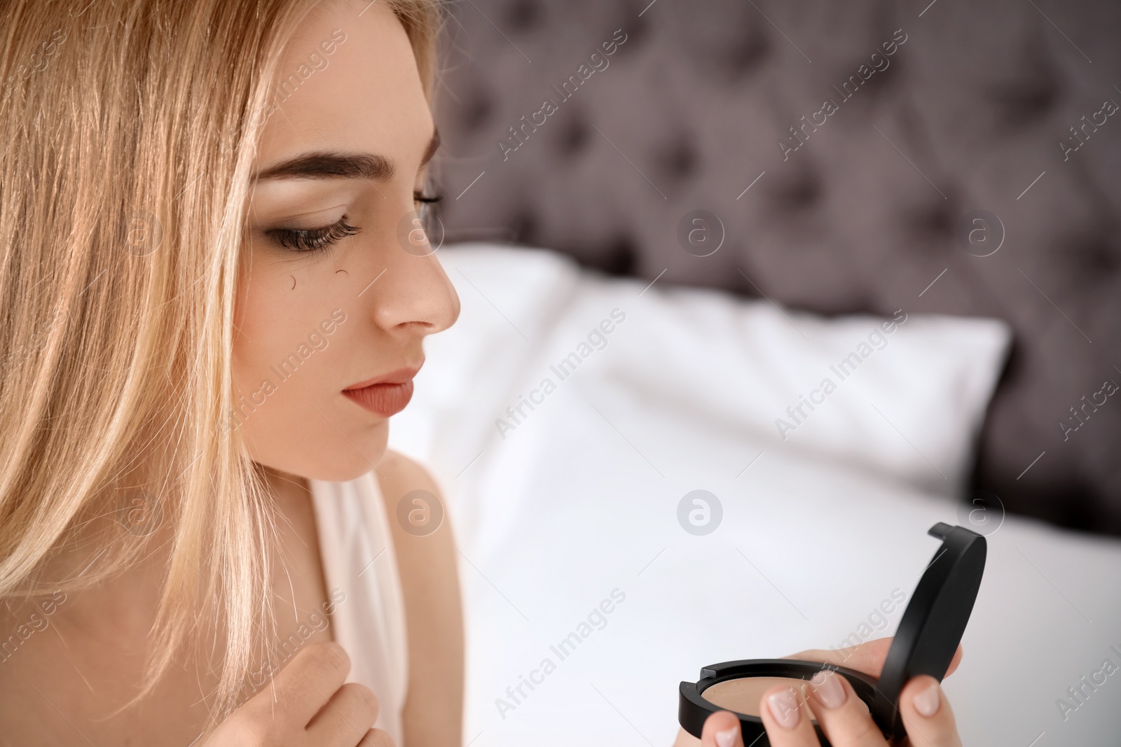 Photo of Young woman with eyelash loss problem looking in mirror indoors