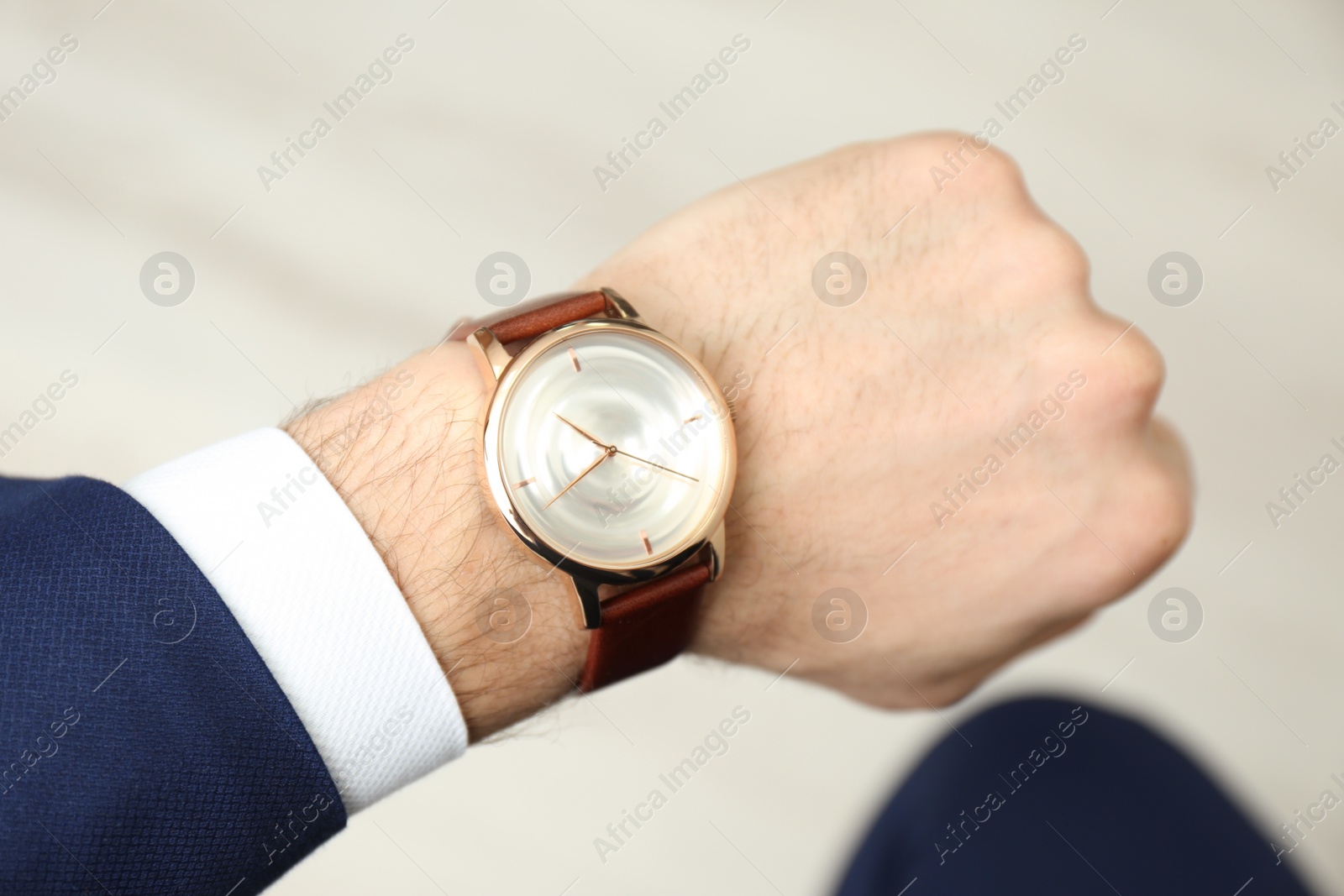 Photo of Businessman with luxury wrist watch on blurred background, closeup