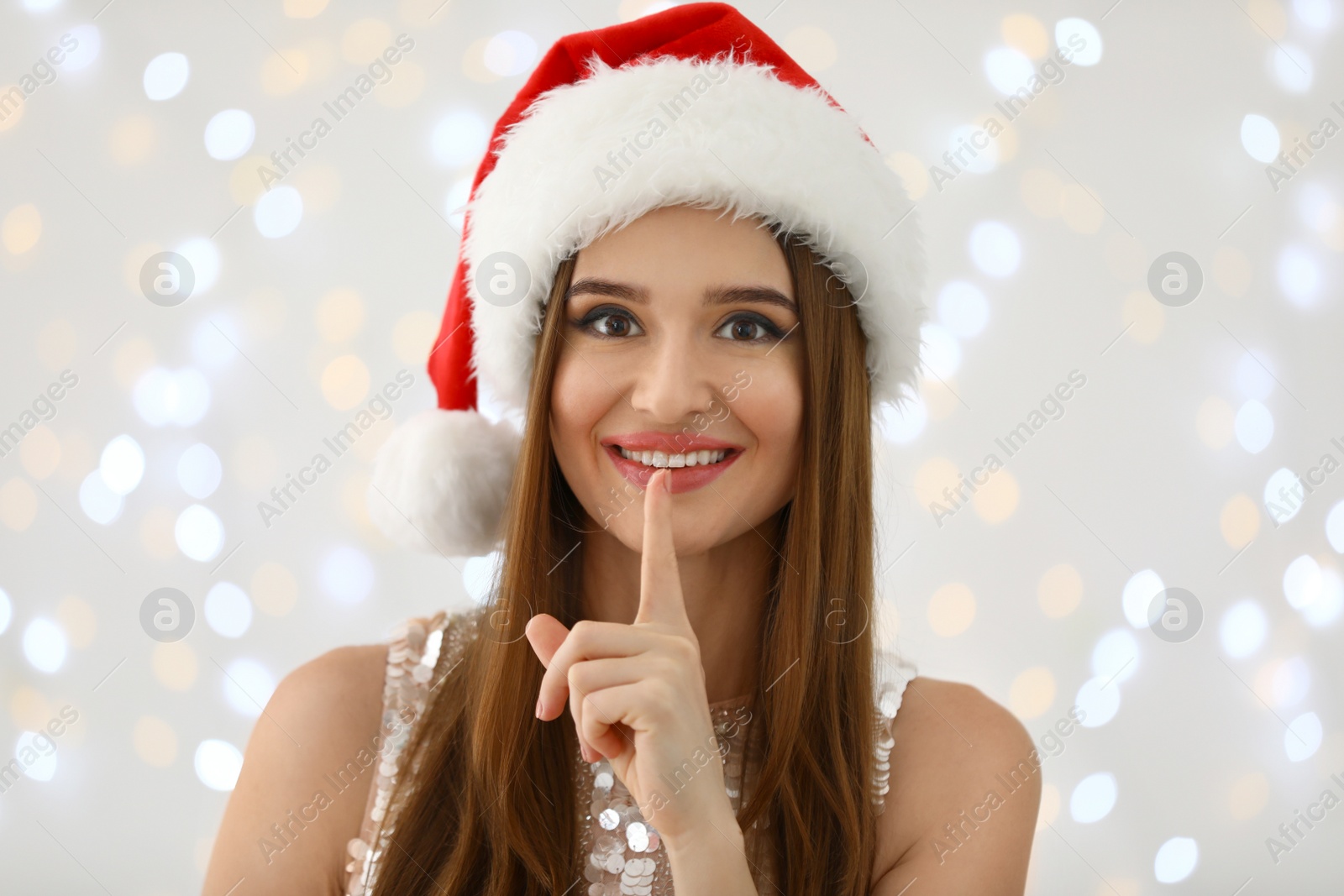 Photo of Happy young woman in Santa hat against blurred Christmas lights