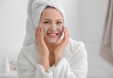 Woman with scrub on face in bathroom