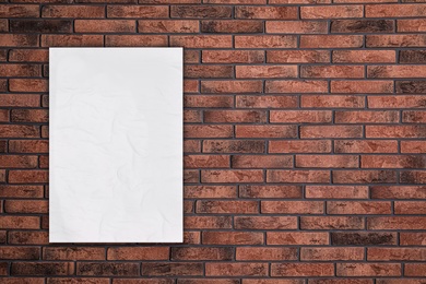 Image of Blank creased poster on brick wall. Mockup for design 