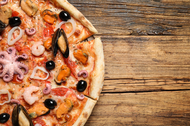 Photo of Delicious seafood pizza on wooden table, top view. Space for text