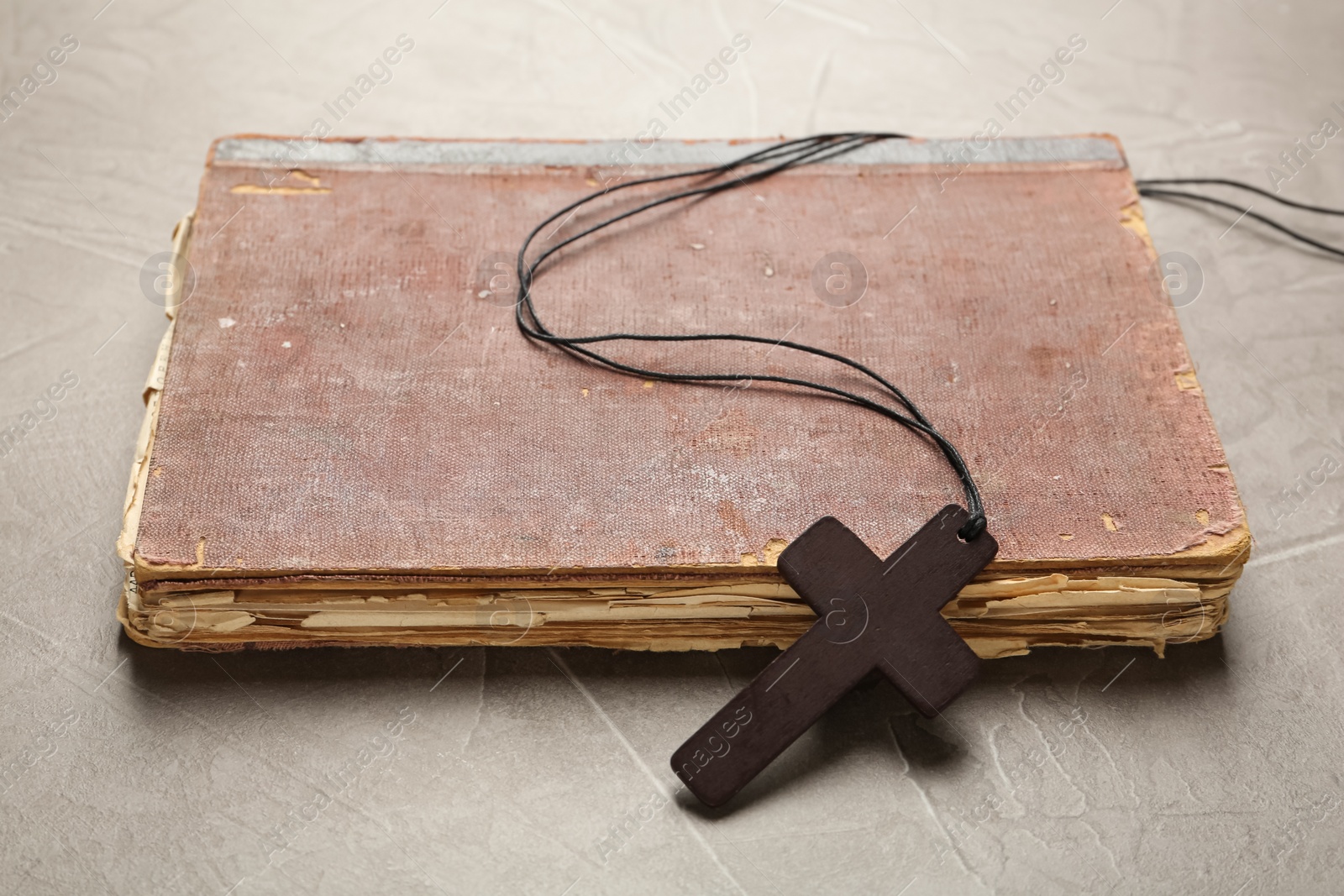 Photo of Wooden Christian cross and old Bible on grey table