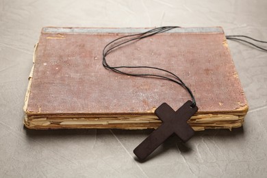 Photo of Wooden Christian cross and old Bible on grey table