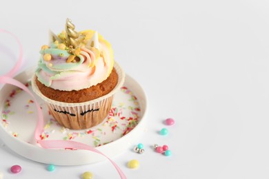 Photo of Cute sweet unicorn cupcake on white table, space for text