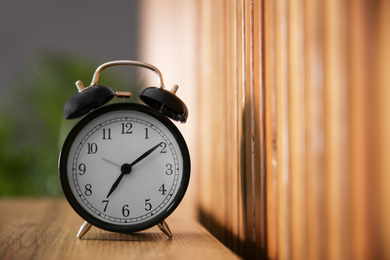 Alarm clock on wooden table at home. Morning time