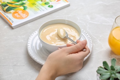 Photo of Woman with vanilla pudding at table, closeup