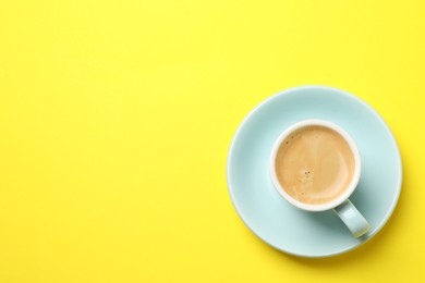 Photo of Aromatic coffee in cup on yellow background, top view. Space for text