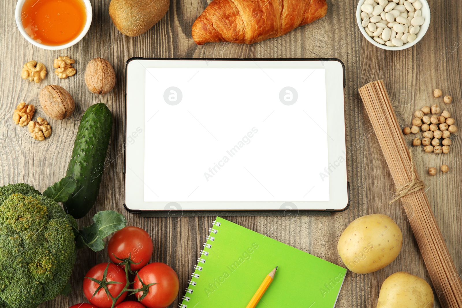 Photo of Glycemic index. Tablet with blank screen, different products and notebook on wooden table, flat lay