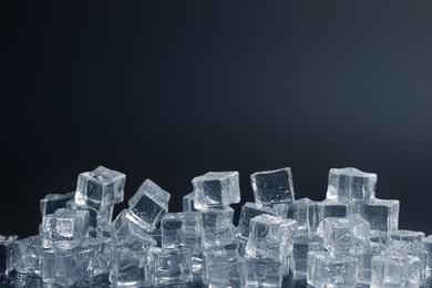 Photo of Crystal clear ice cubes with water drops against black background. Space for text