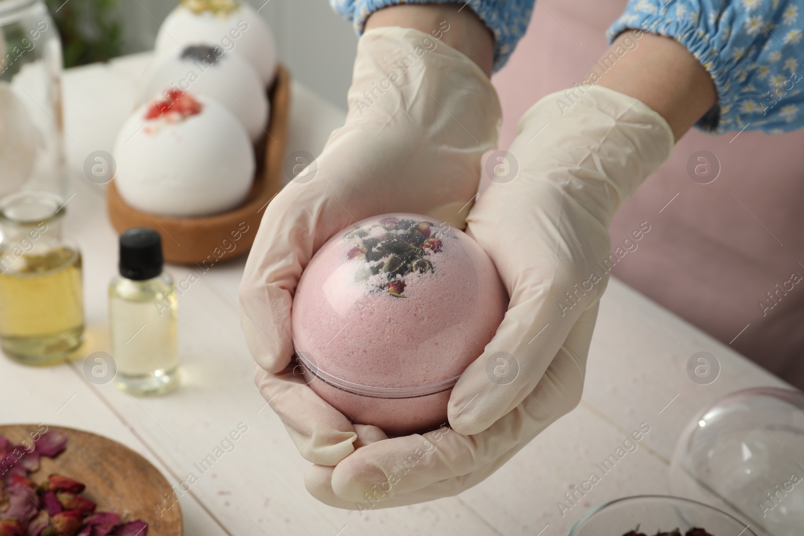 Photo of Woman in gloves making bath bomb at white table , closeup