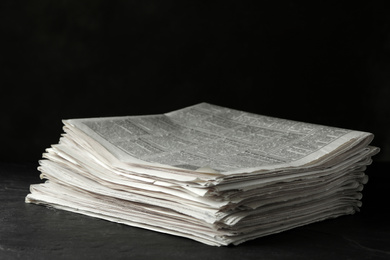 Photo of Stack of newspapers on dark stone table. Journalist's work