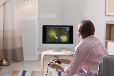 Photo of Young woman playing video games at home