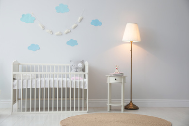 Photo of Stylish baby room interior with crib and decor elements