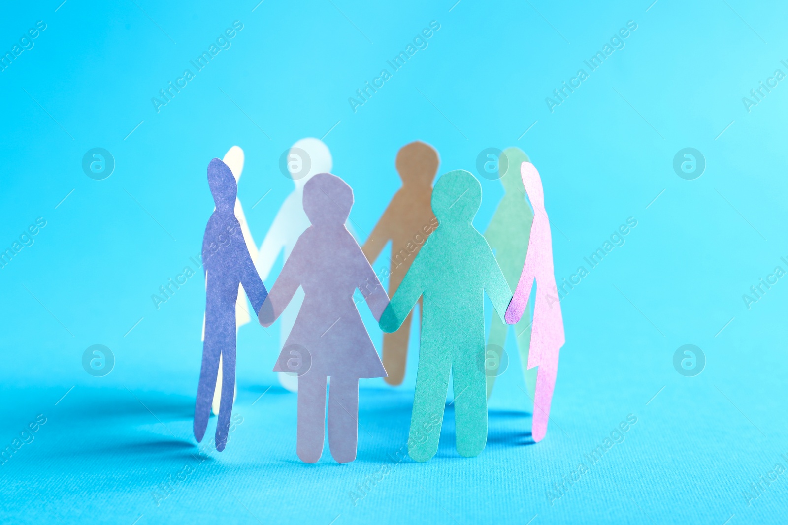 Photo of Paper human figures making circle on turquoise background. Diversity and Inclusion concept
