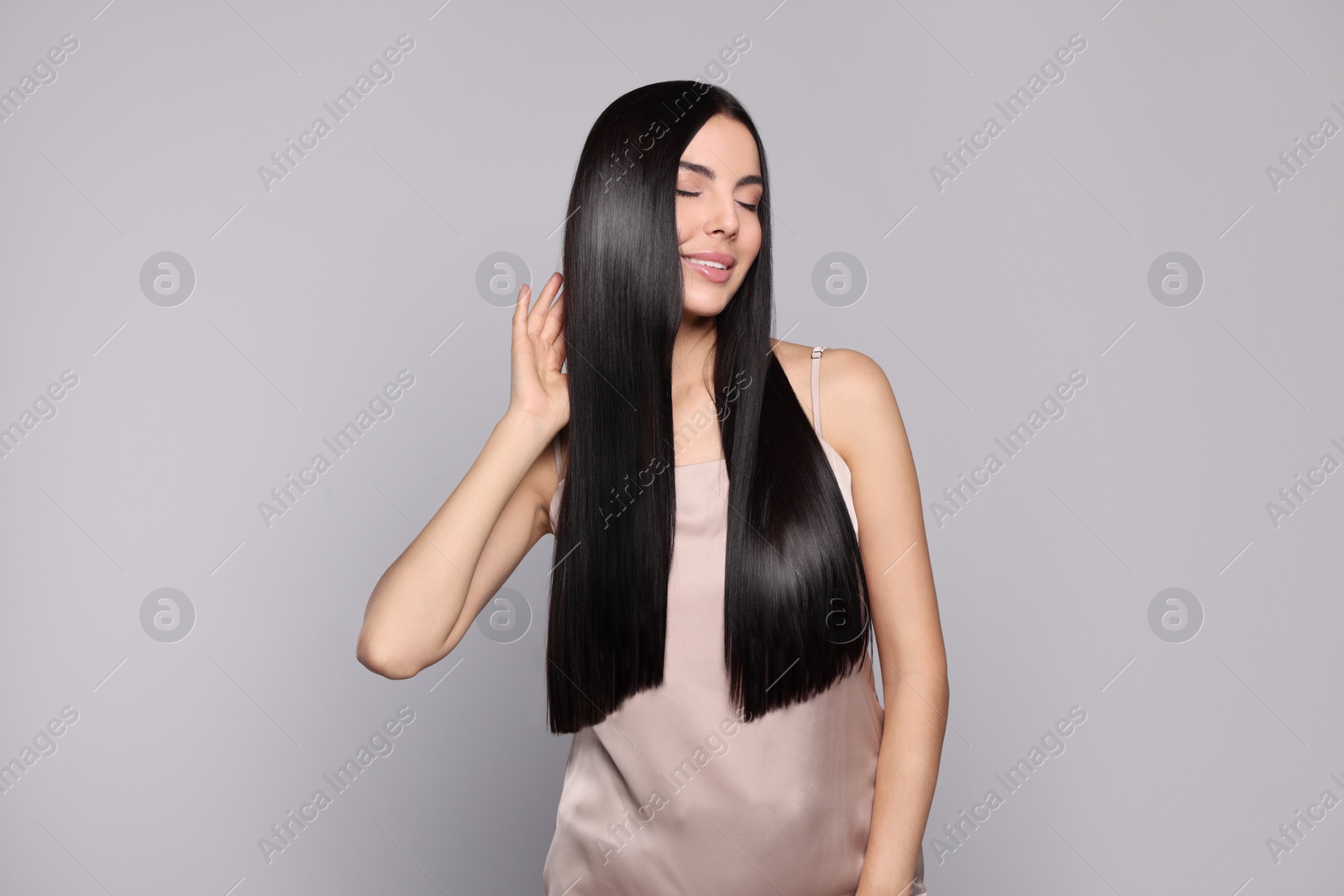 Photo of Portrait of beautiful young woman with healthy strong hair on light grey background