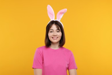 Photo of Easter celebration. Happy woman with bunny ears on orange background