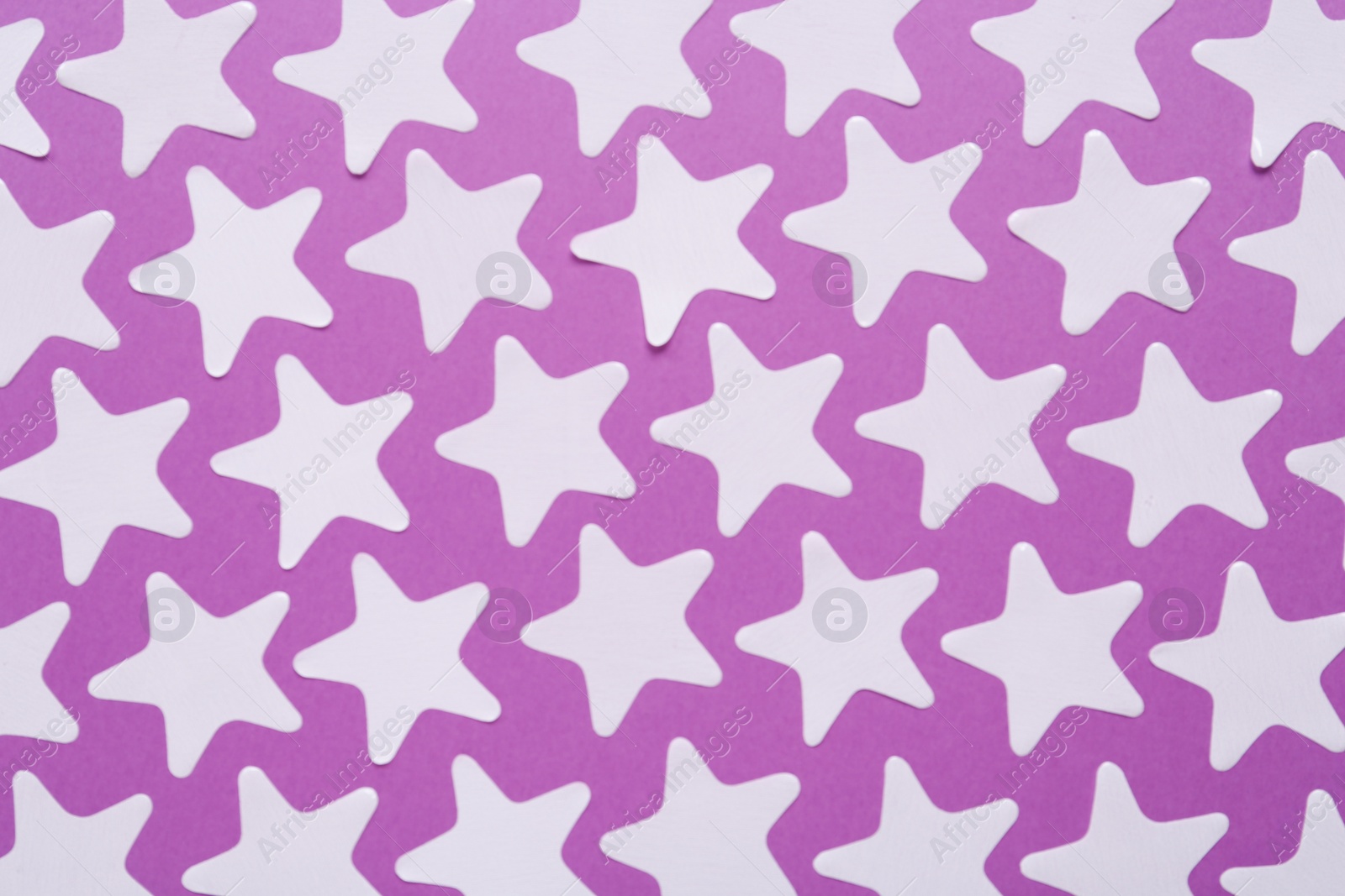 Photo of White star shaped confetti on violet background, flat lay