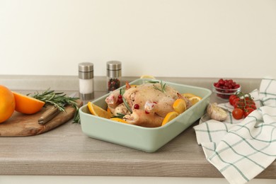 Photo of Chicken with orange slices in baking pan on wooden table