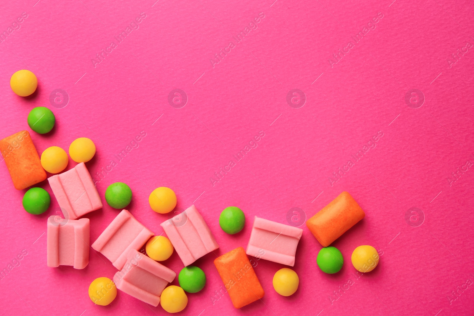 Photo of Many different chewing gums on pink background, flat lay. Space for text