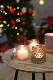 Photo of Burning candles on wooden table in room decorated for Christmas