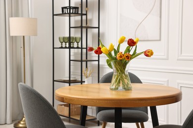 Photo of Stylish dining room interior with comfortable furniture and beautiful tulips