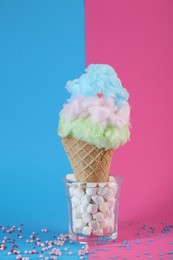 Photo of Sweet cotton candy in waffle cone on color background