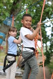 Photo of Little children climbing in adventure park. Summer camp