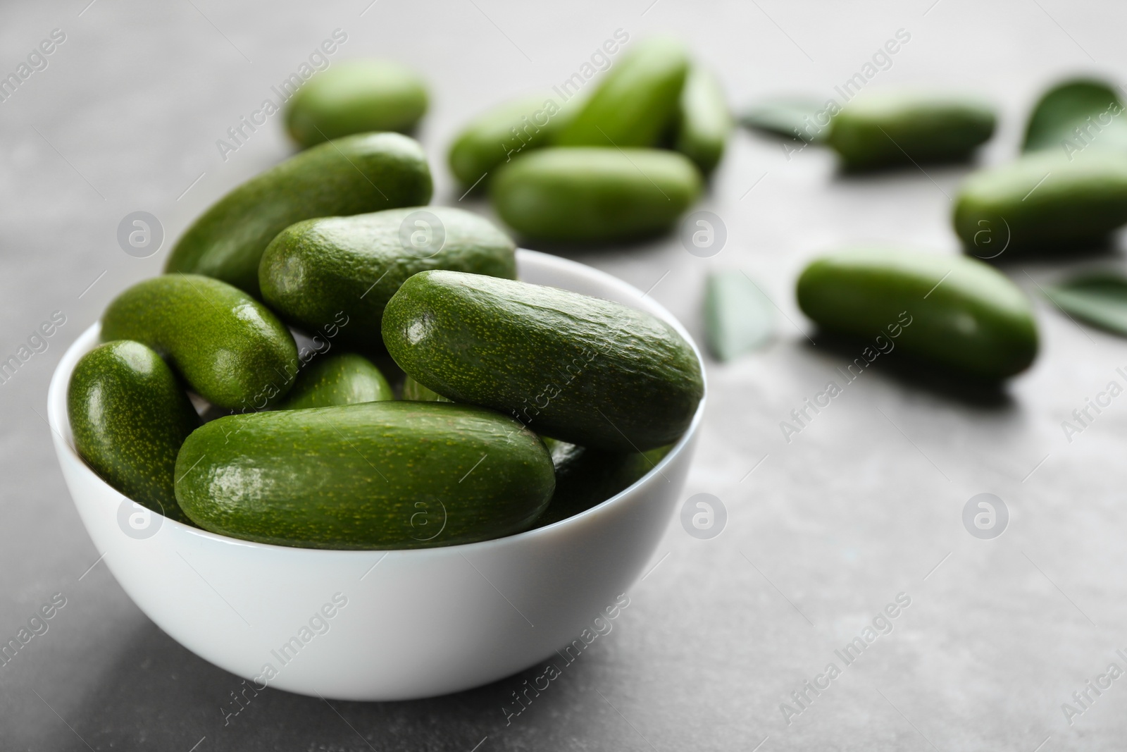 Photo of Bowl with fresh seedless avocados on grey table, closeup