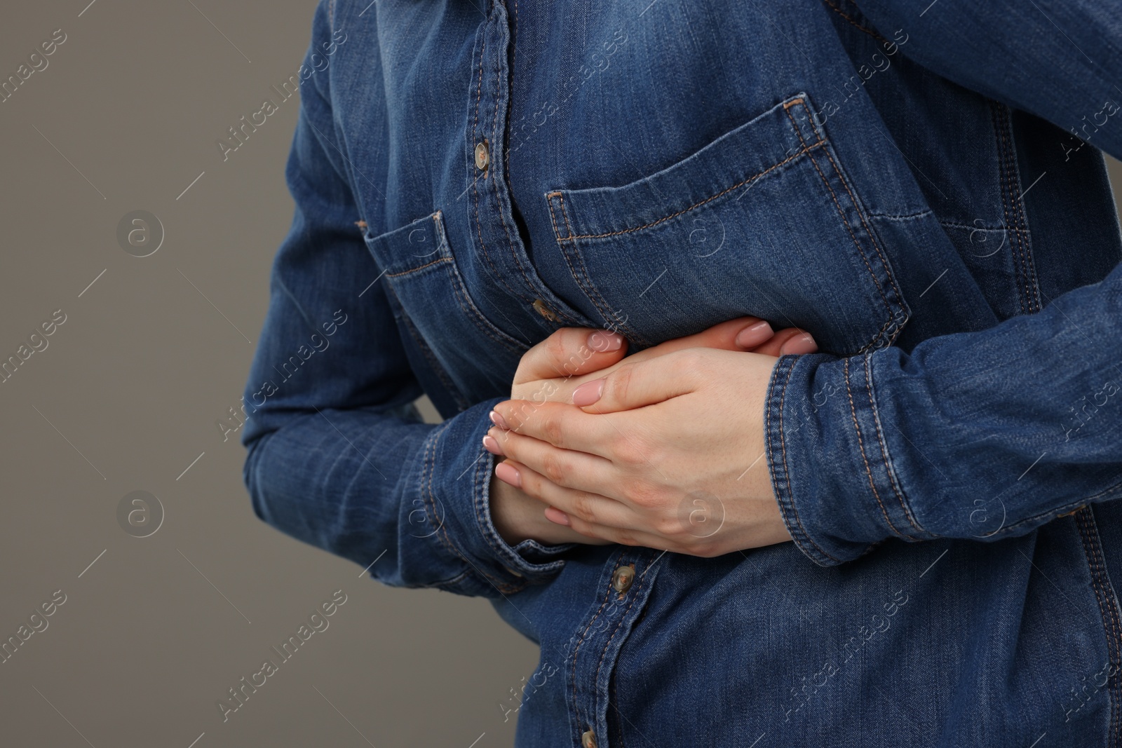 Photo of Woman suffering from stomach pain on grey background, closeup