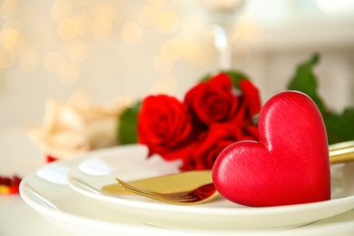 Photo of Romantic table setting with red heart against blurred lights, space for text. Valentine's day celebration