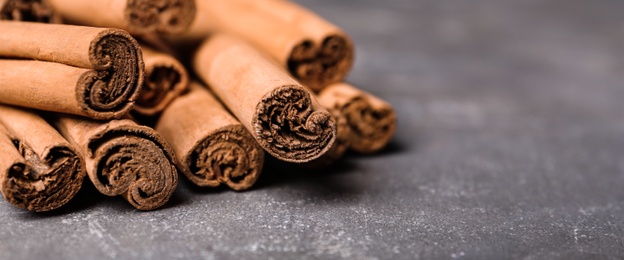 Aromatic cinnamon sticks on grey table, closeup