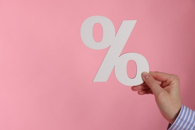 Photo of Woman holding percent sign on pink background, closeup. Space for text