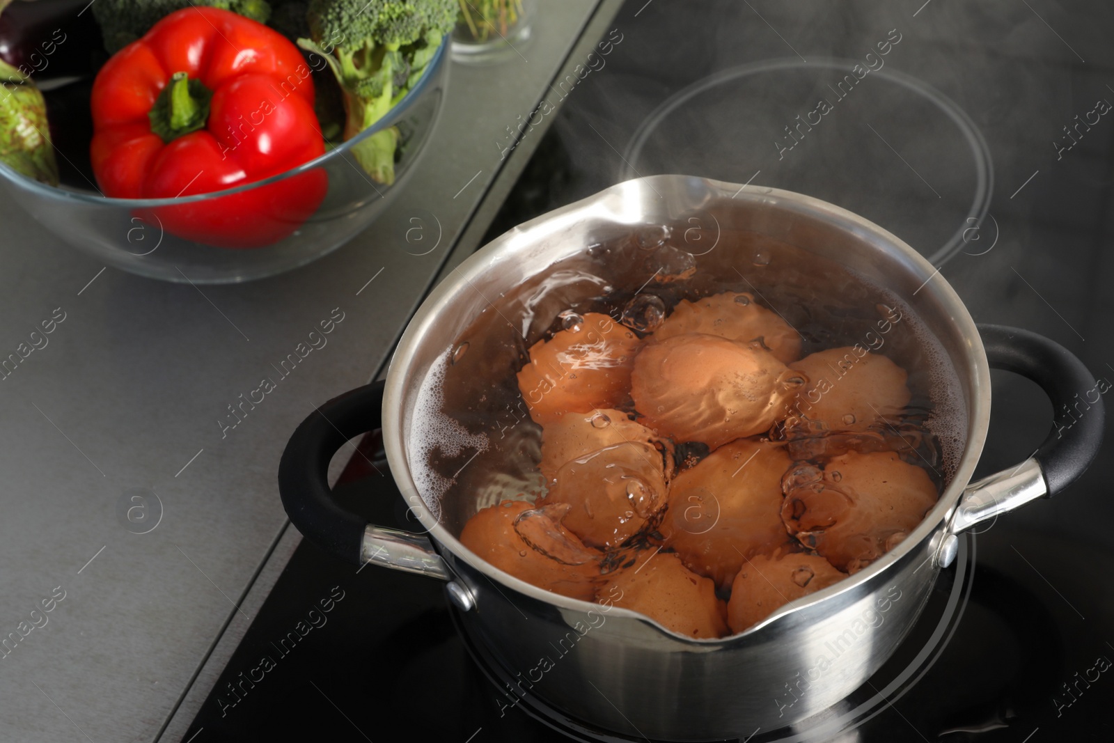 Photo of Cooking chicken eggs in pot on electric stove at kitchen