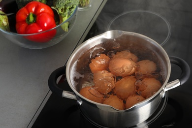 Cooking chicken eggs in pot on electric stove at kitchen