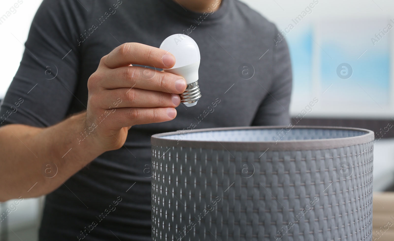 Photo of Man changing light bulb in lamp indoors, closeup