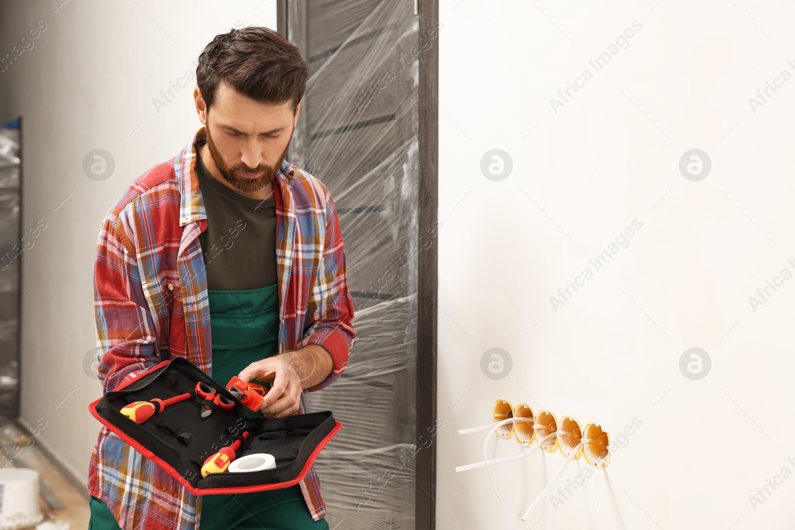 Photo of Electrician taking pilers from tool bag indoors