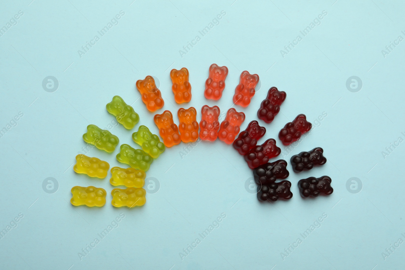 Photo of Delicious gummy bear candies on light blue background, flat lay