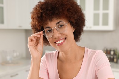 Portrait of happy young woman with eyeglasses in kitchen