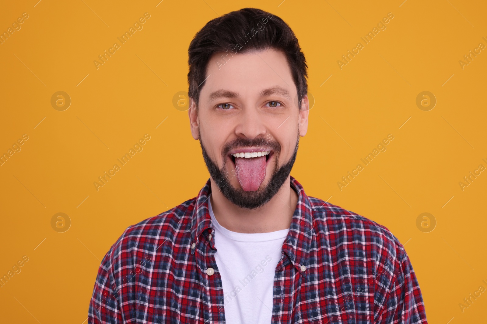 Photo of Happy man showing his tongue on orange background