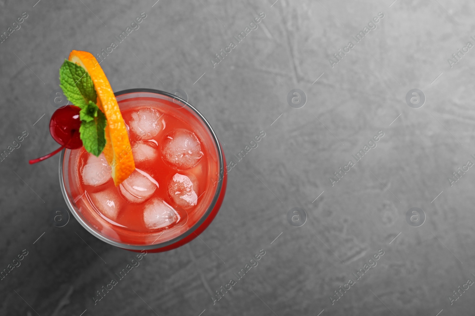 Photo of Glass of tasty refreshing cocktail on grey background, top view. Space for text