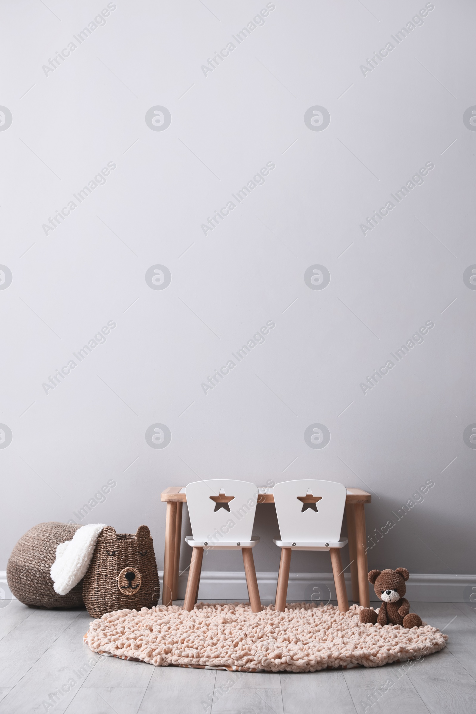 Photo of Cute child room interior with furniture and toy near light grey wall. Space for text