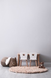 Photo of Cute child room interior with furniture and toy near light grey wall. Space for text