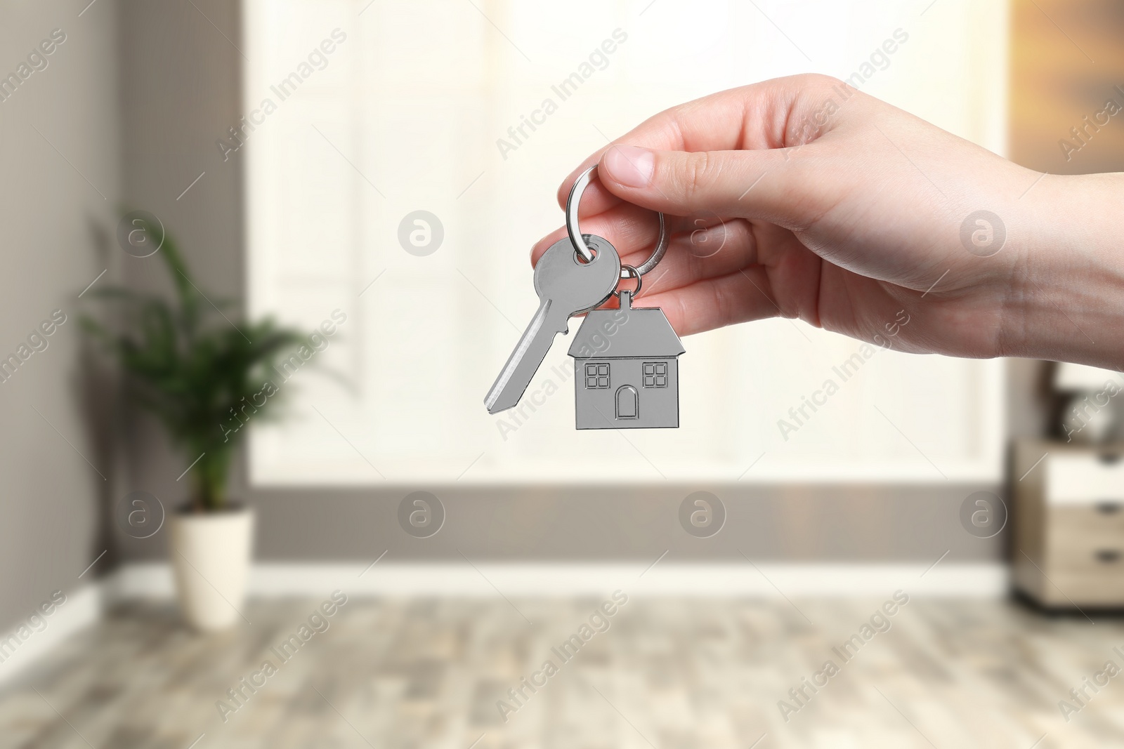 Image of Woman holding house key in room, closeup